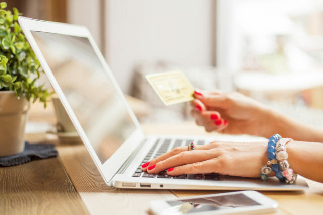Woman's hand holding credit card in front of laptop
